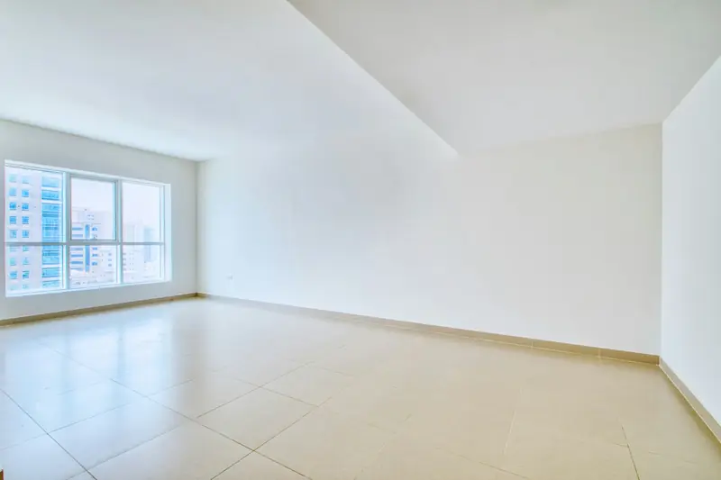 Empty apartment living room with white walls, a tiled floor and large windows