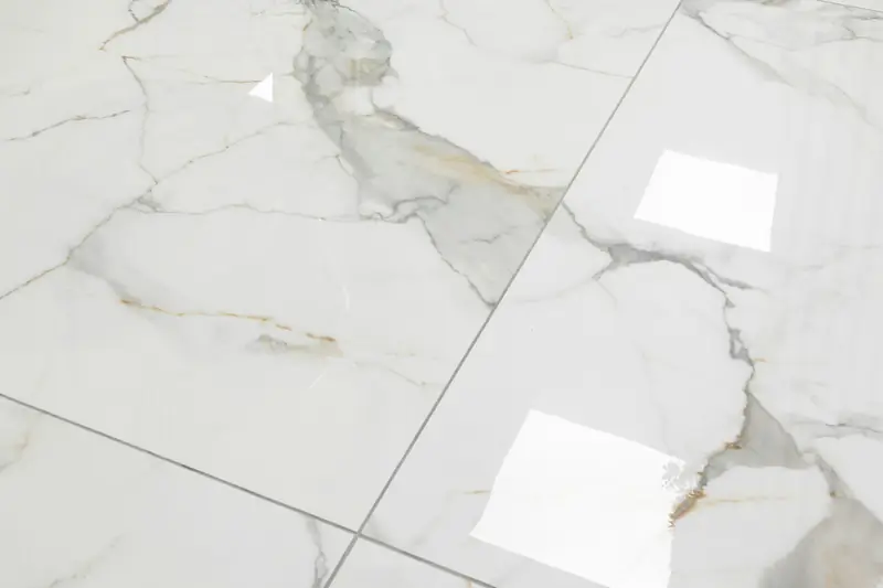 Close view of a glossy white marble-effect floor with grey and gold veining