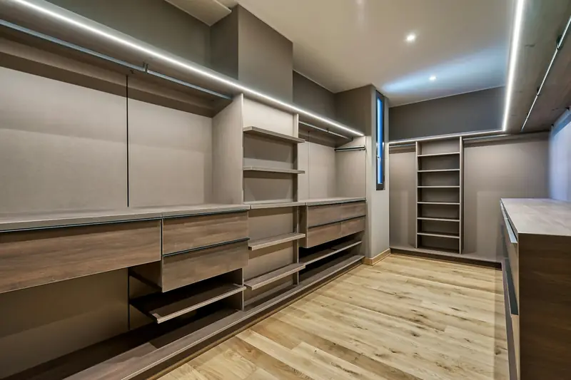 Walk-in wardrobe with timber-finish drawers, open shelving and LED strip lighting