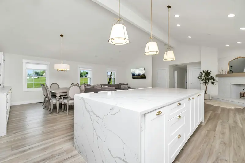 Bright open-plan kitchen with a white marble waterfall island and pendant lights