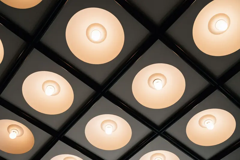 Dark coffered ceiling with round pendant lights glowing warm white