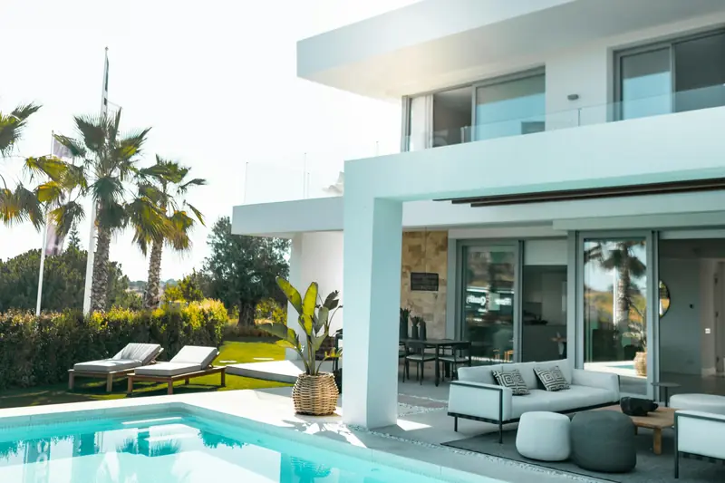 Modern white two-storey villa with a swimming pool, sun loungers and palm trees